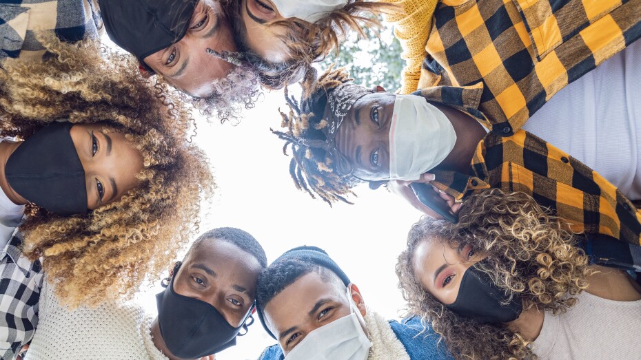 group of friends hugging each other smiling wearing a mask to protect themselves
