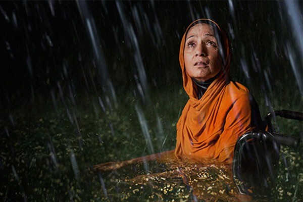 A Muslim woman in a wheelchair surrounded by flood waters.