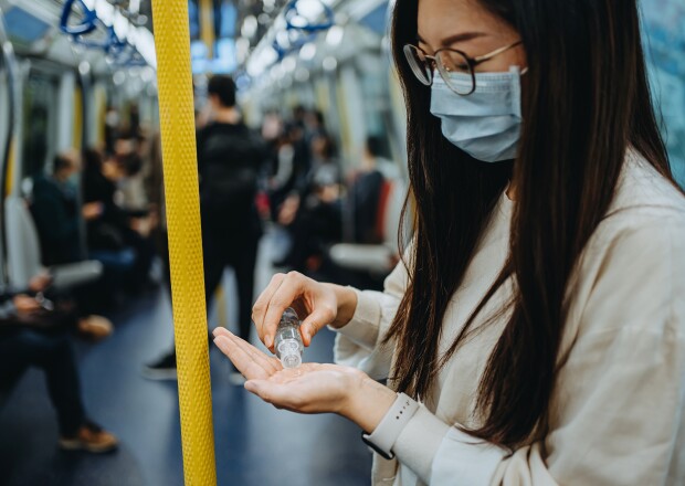 Woman cleaning hands with hand sanitizer riding on subway