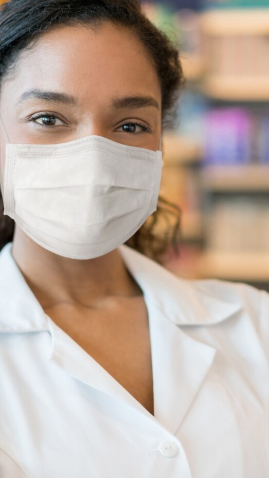 mujer que trabaja en una farmacia con una mascarilla
