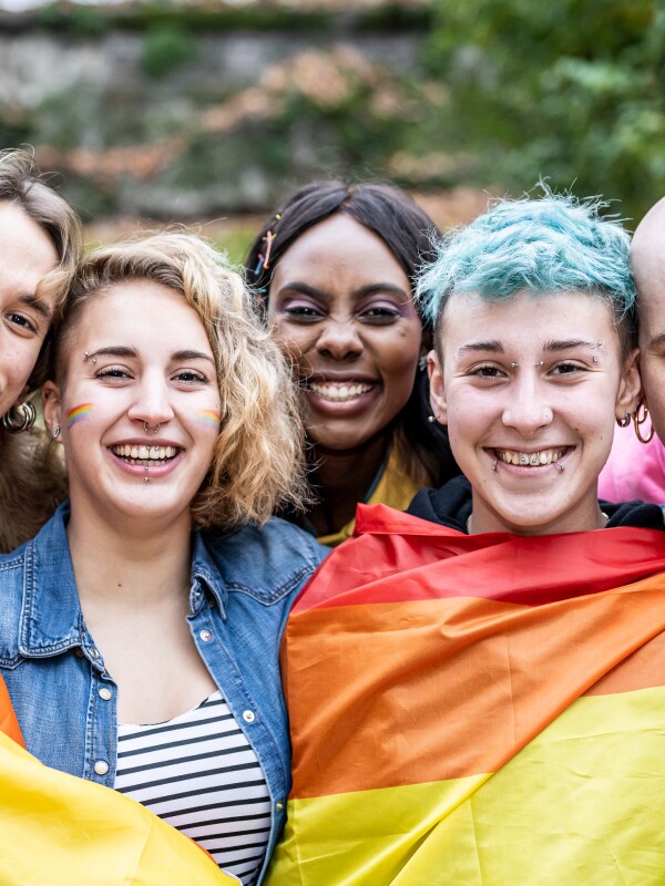 Multi-racial group with different sexual orientations and rainbow flag around their shoulders