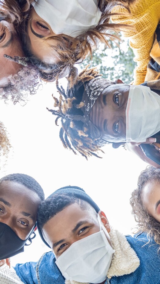 group of friends hugging each other smiling wearing a mask to protect themselves